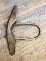 Full top-down view of wooden antique ox yoke on wooden floor showing central beam and arch detail.