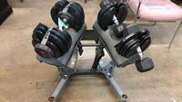 Angled top view of two adjustable dumbbells on stand