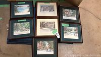 Nine framed art prints stacked and leaning, showing variety of frames and sizes