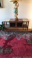 Full view of the wood console table with decorative elements and a figurine lamp on top (lamp not included). Shows the overall design and proportions.