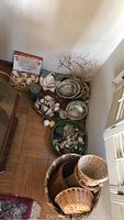 Lot of shells, baskets, candles, and decorative coral pieces arranged on floor corner.