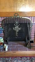 Full front view of the fireplace screen and fireplace tools on a brick hearth.