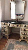 Full view of the vanity desk with black stone surface and large mirror mounted above.