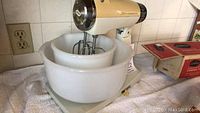 Vintage Sunbeam Mixmaster stand mixer with two white mixing bowls on countertop