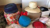 Image showing vintage woven hats in navy blue, blue, red felt hat, and a wide-brim straw hat on boxes.