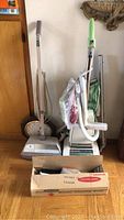 Photo of two upright vacuum cleaners, one Hoover and one Kenmore, with cleaning attachments and accessories packed around them.