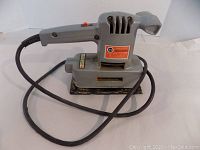 Photo of the Black & Decker 5710 dual action deluxe sander showing the whole unit with its power cord and sanding base, gray plastic body, ergonomic handle.