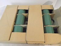 Two cardboard boxes containing 12 green mugs, 6 per box, stacked and neatly packed.