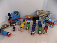 Wide view of all Thomas the Train toys and boxed Home Hardware delivery truck toys on a table