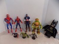 Photo showing full lot with 10" to 12" Captain America, 2 Spider-Man, a Teenage Mutant Ninja Turtle figure, a Batman alarm clock, and three small busts of Hulk, Silver Surfer, and Captain America in front.