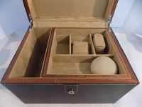 Open leather wood jewelry case arranged to show compartments for rings, bracelets, and other items with padded holders and cushioned section.