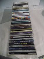 Stack of 35 music CDs showing spines and cases in varying condition