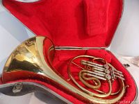 French horn resting in open red plush-lined case