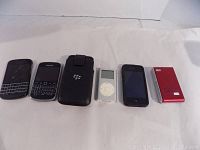 Photo showing all six items lined up: 3 BlackBerry phones, BlackBerry case, Apple iPod Classic, iPhone 3GS, and red River MP3 player.