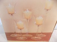 Set of 5 glass candle holders arranged with candles inside, showing varying heights and design.