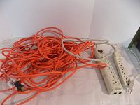 View of the orange 30m Noma 16 gauge outdoor extension cord plugged into the power bars.