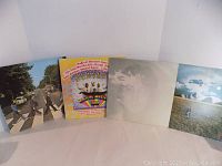Four vinyl albums by The Beatles and John Lennon with original covers, showing some wear.