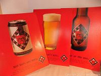 Three Red Dog beer posters with red background, showing a can, bottle, and glass of beer, arranged side by side.