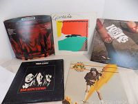 Photo of all five vinyl albums standing upright and lying flat showing cover art and titles of Thin Lizzy, Genesis, Kinks, AC/DC, and one partially visible album