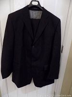Front view of men's black pinstripe Calvin Klein suit jacket on hanger.