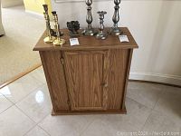 Front view of wood grain fish tank stand with six candle holders on top, three brass and three silver-toned