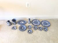 Full set of Wedgwood jasperware pieces laid out showing various shapes and white classical relief designs on blue matte finish.