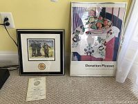 Framed print of Emmett Kelly clown figure with certificate of authenticity on carpet floor next to a framed Picasso poster.