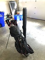 Full set of Orlimar golf clubs in black golf bag with stand in a garage environment