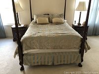 Full bed view showing comforter, pillows, and bed skirt on a four-poster wooden bed frame