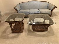 Two Lane brand glass top tables including a coffee table and a side table placed side by side in a carpeted room with a blue upholstered sofa in the background.