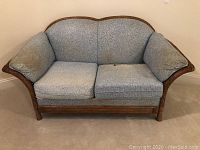 Front view showing blue fabric cushions and wooden wicker frame.