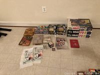 Wide shot showing all items spread on floor including boxed card sets, trivia games, a signed baseball, handkerchiefs, loose cards, and small boxes.