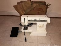 Full side view of the Singer sewing machine with foot pedal and damaged box in background.