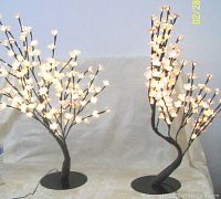 Pair of Japanese cherry blossom style lamps with warm white lights and pink petals on brown wrapped branches standing on black round bases.