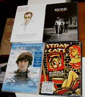 Front view of all four DVDs showing box art and titles: Elton John Greatest Hits, George Harrison Living in the Material World, Stray Cats Rumble in Brixton, Keane Strangers.