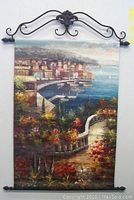 Full vertical view of tapestry hanging on wrought iron rod showing coastal village and floral landscape