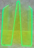 Front and angled side view of fluorescent green acrylic magazine stand showing its translucent material and construction.