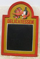 Front of delicatessen sign showing raised prawn, wine bottle, fruit, 'DELICATESSEN' text, and chalkboard panel.