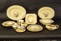 Overview of various pieces: serving platters, bowls, sugar bowl with lid, cream jug, gravy boat with tray, teacup and saucer, stack of plates