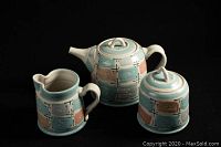 Front view of a three-piece pottery tea set with a teapot, creamer, and lidded sugar bowl featuring patchwork pastel colors.