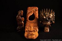 Three wooden carvings: Indonesian musician with drum, vertical carved wooden face mask, dark painted mask with tongue out and spikes
