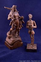 Front view of carved wood statues of William Tell with son and Cervantes