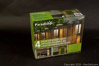 Front view of the box showing Paradise brand logo, the number 4 for quantity, product name in three languages, and images demonstrating use of the solar LED accent lights outdoors.