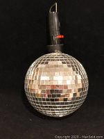 Disco ball front view showing mirrored surface, upper battery compartment, and missing mirrors at top.