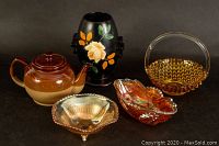 Photo of teapot, Gresham vase, carnival glass bowls, and amber glass basket arranged together