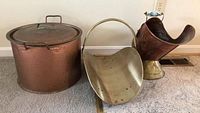 Photo showing large copper pot with lid, brass ash bin, and the brass log carrier with ceramic handle.