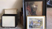 Front view of three framed art pieces with two being recognizable artworks and one empty frame visible in front