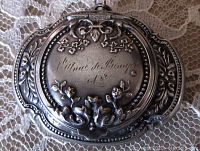 Closed front side view showing detailed repousse floral design with inscription 'St Anne de Beaupre'.
