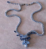 Full view of the vintage Sherman necklace laid flat showing light blue and sapphire crystals with hook clasp.