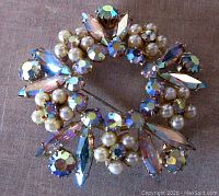 Front view of vintage Sherman brooch showing aurora borealis round and marquise crystal stones with pearl flowers in gold plated setting.